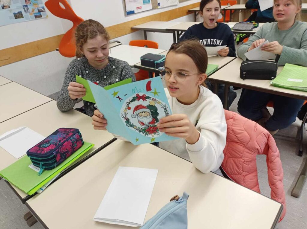 Schüler in Klassenzimmer lesen eine Weihnachtskarte.