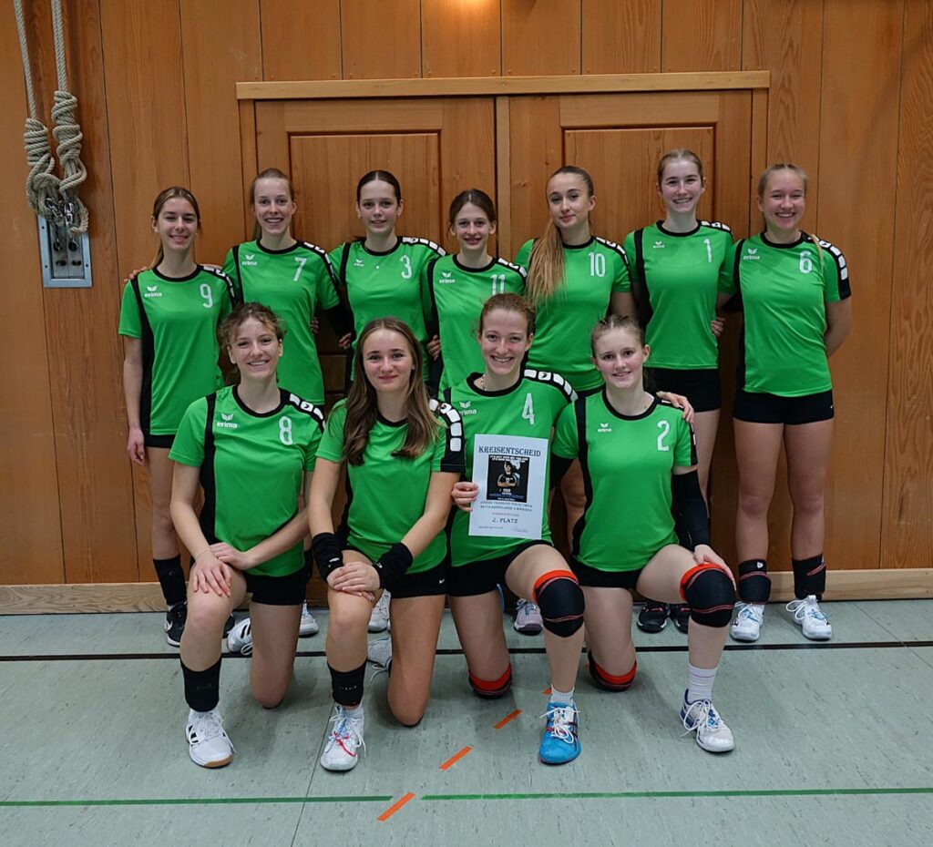 Gruppe von Volleyballspielerinnen in grünen Trikots posiert