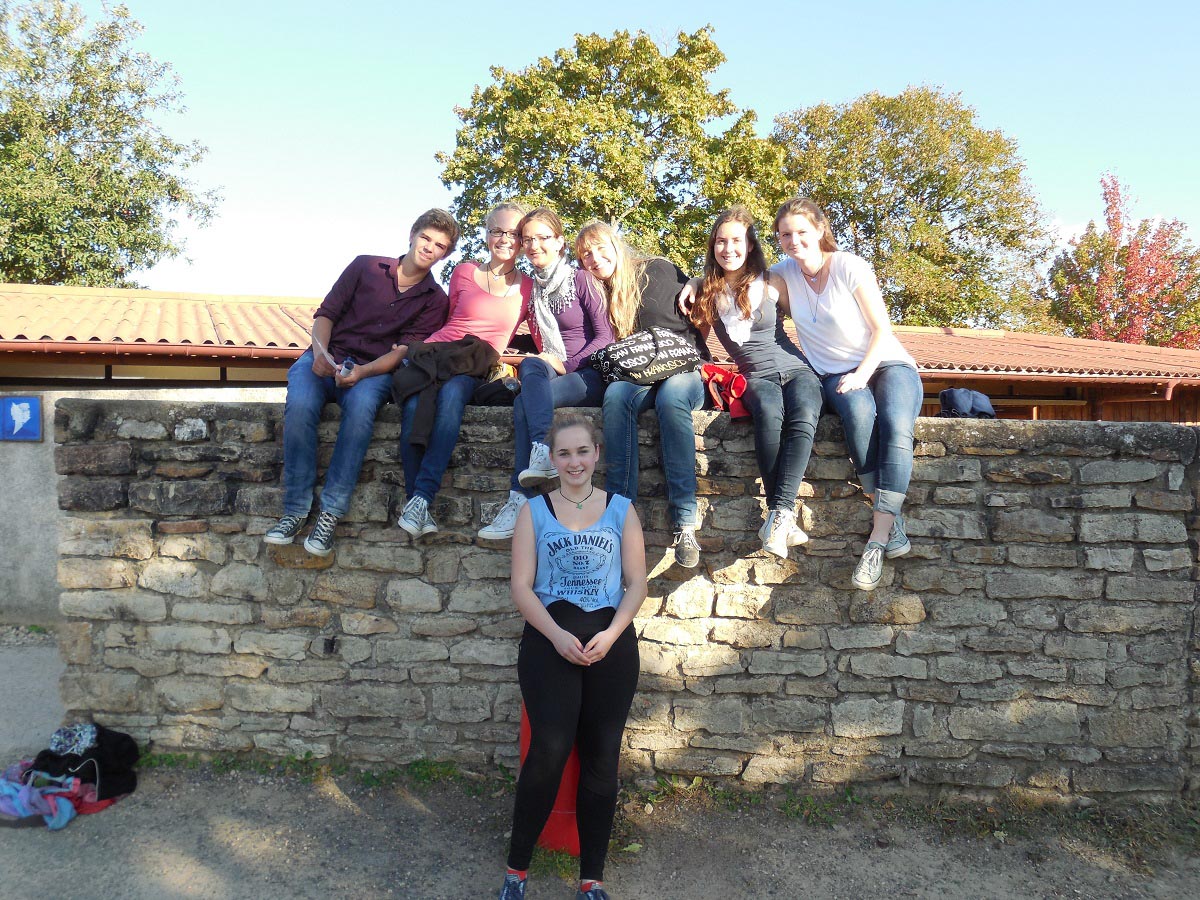 Gruppe junger Leute sitzt auf einer Mauer